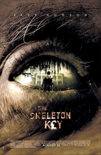 Primo piano di un occhio umano che riflette una figura in ombra seduta davanti a una casa circondata da alberi e muschio spagnolo, con atmosfera cupa e inquietante. Il testo sulla locandina riporta KATE HUDSON in alto, THE SKELETON KEY con un simbolo a forma di chiave e AUGUST 12 in basso.