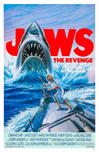 Un enorme squalo con la bocca spalancata emerge dall’oceano minacciando una persona in piedi sulla prua di una barca danneggiata. La scena è intensa e drammatica, con onde che si infrangono e cielo blu sullo sfondo. In alto, grande testo rosso: JAWS; sotto, testo più piccolo: THE REVENGE e This Time Its Personal. In basso sono elencati cast e crediti in testo blu e bianco.