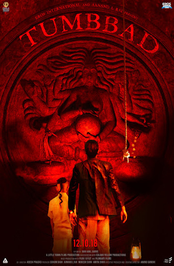 Locandina del film Tumbbad: un uomo e un bambino sono rivolti verso una grande scultura di pietra raffigurante una dea con molte braccia che tiene un globo, una corda scende dall'alto e delle monete cadono. L'immagine è immersa in una luce rossa che crea un'atmosfera misteriosa e inquietante. Testo visibile: TUMBBAD, 12.10.18. Il tono generale è cupo e carico di suspense.
