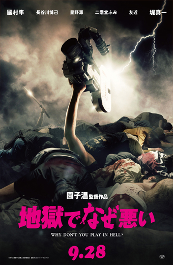 Locandina del film Why Don’t You Play in Hell. Un braccio sollevato tiene una grande cinepresa sopra una pila di persone sdraiate a terra, con illuminazione drammatica e fulmini sullo sfondo. La scena è caotica e intensa, trasmette una sensazione di lotta e passione per il cinema. Sulla locandina sono presenti caratteri giapponesi e la scritta in inglese Why Don’t You Play in Hell, oltre alla data di uscita 9.28.