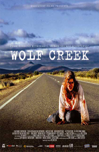 Donna sconvolta con abiti macchiati di sangue inginocchiata al centro di una strada deserta che attraversa l'outback australiano sotto un cielo drammatico. Sopra di lei spicca il titolo del film Wolf Creek in grandi lettere bianche, con il sottotitolo in italiano Come possono ritrovarti se non sei mai scomparso. Il tono generale è teso e inquietante.